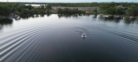 An aerial view of a boat crossing a lake