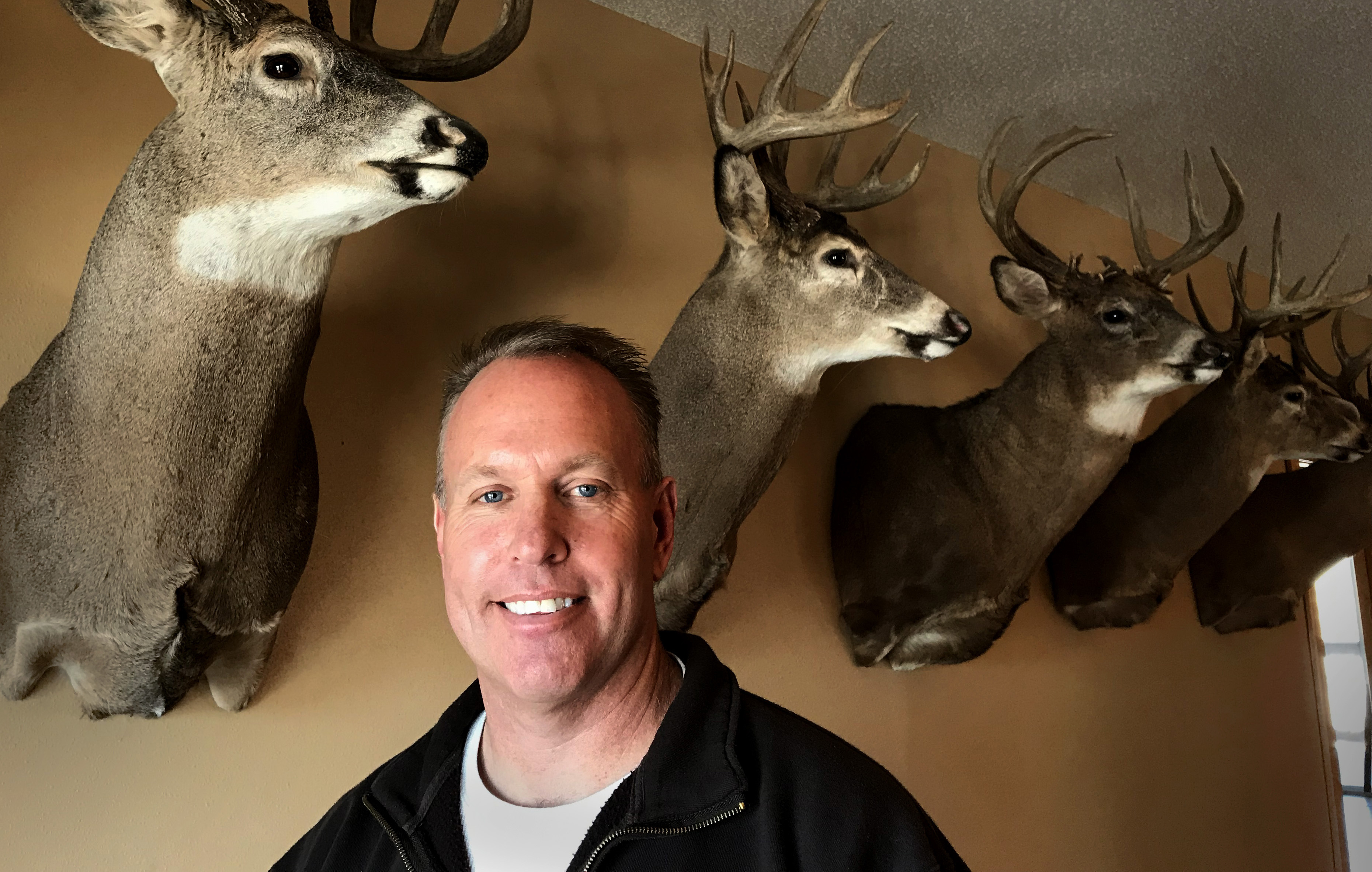 man in front of trophy bucks mounted on the wall