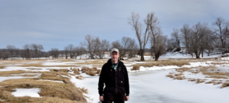 Man stands at the bend of a frozen river
