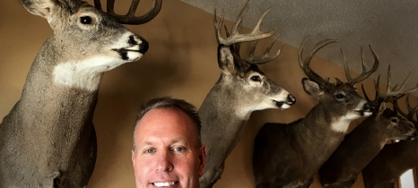 man in front of trophy bucks mounted on the wall