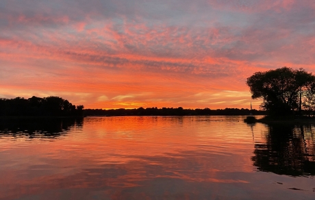 Clouds and sun reflect orange and pink in North Center Lake