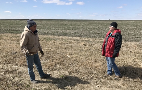 Farmer and SWCD staff member stand in a field where a cover crop greens up on March 31