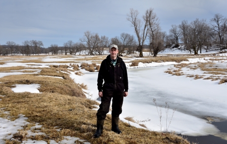 Man stands at the bend of a frozen river