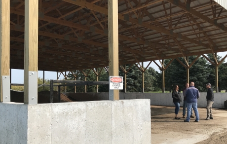 three people standing under a covered manure storage area