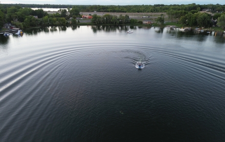 An aerial view of a boat crossing a lake