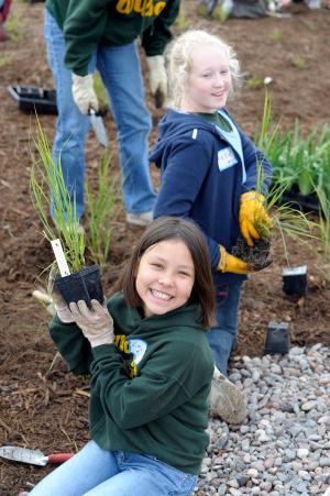 Kids planting grasses and wildflowers during a planting event